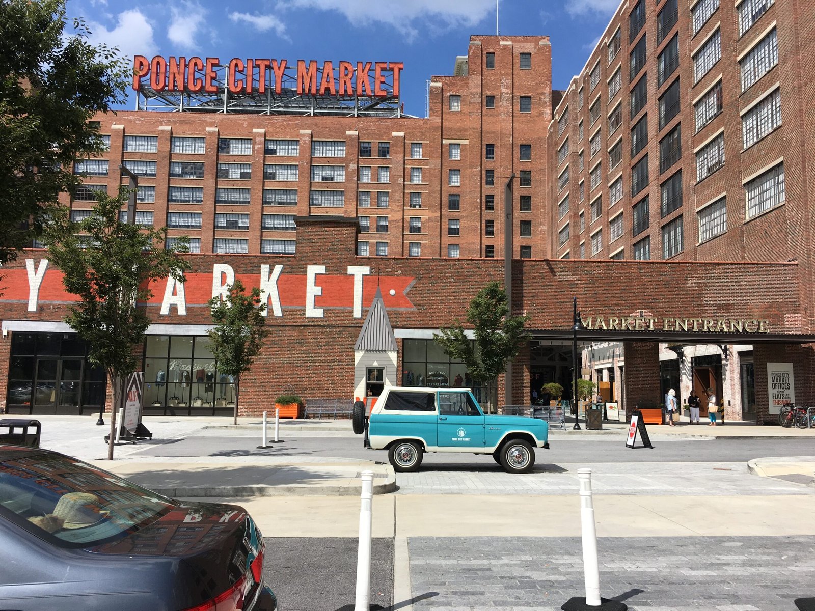 Red Ponce City Market sign above the brick building and courtyard entrance.