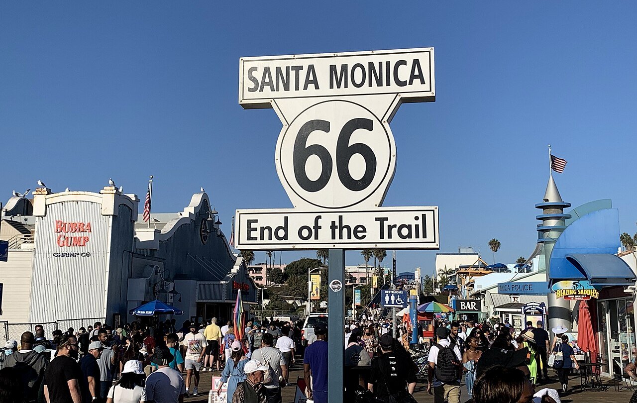 Route 66 End of the Trail sign on the busy Santa Monica Pier in California.